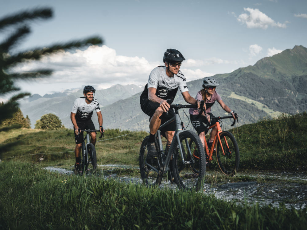 Three gravel bikers ride through the impressive mountain landscape of the Hohe Tauern near Mittersill.