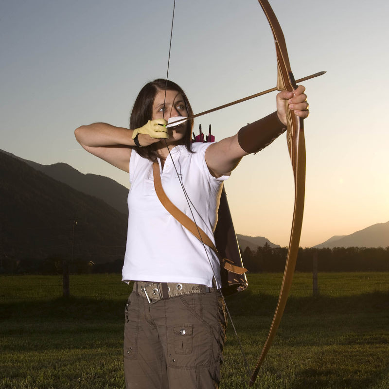 Woman archery in Mittersill, with the Alps in the background as the sun sets at dusk.