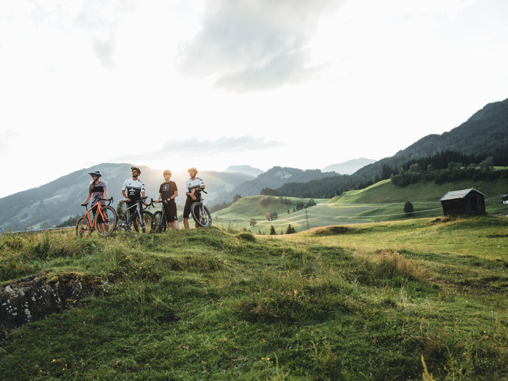 Four mountain bikers traverse the Kitzbühel Alps, surrounded by the impressive mountains of the region.