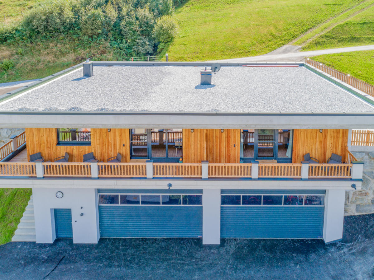 A bird's eye view of the Hoferlitzlhubgut in Mittersill, nestled in the picturesque Alpine landscape on a sunny day.