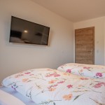 Slaapkamer van het Hoferlitzlhubgut vakantie appartement in Mittersill met tweepersoonsbed en grote TV, ideaal voor ontspannen avonden thumbnail