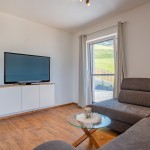 Zithoek met glazen tafel en grootbeeld tv in het stijlvol moderne vakantiehuis Hoferlitzlhubgut in Mittersill. thumbnail