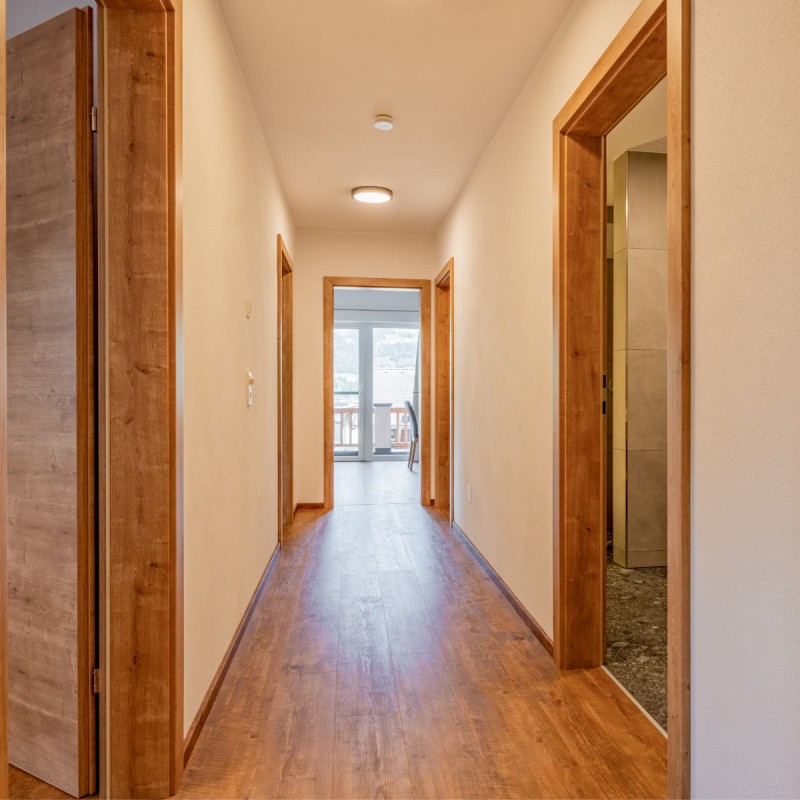 Bright, modern hallway with wooden floor and wooden doors in the Hoferlitzlhubgut vacation apartment in Mittersill.