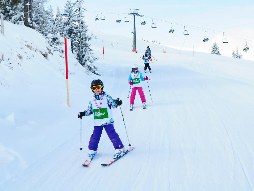 Lachend en plezier makend in de sneeuw skiet de beginnersgroep op de kinderskicursus de piste af op de Resterkogel.