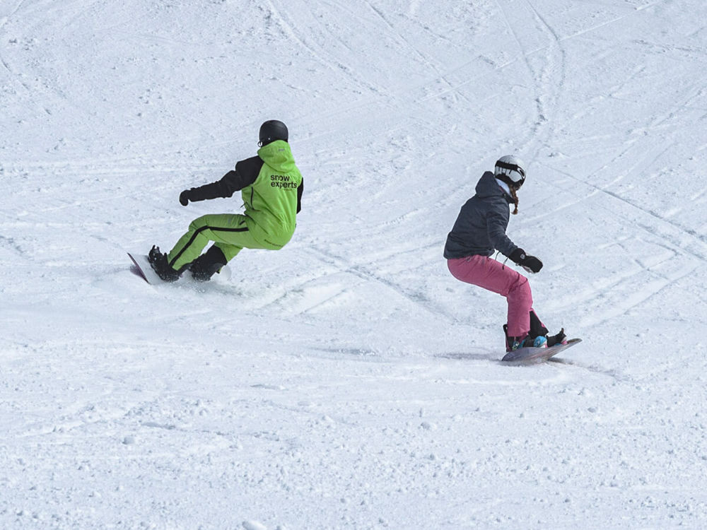 Snowboard instructor with student in the KitzSki ski area during private lessons on the slopes of the Kitzbühel Alps.